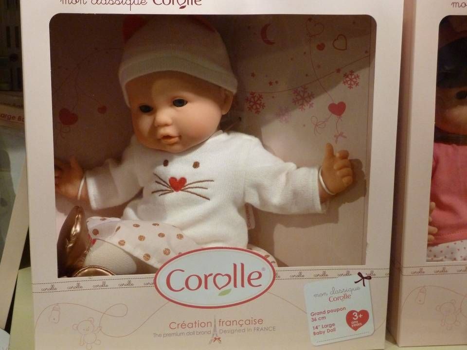 Poupée Corolle en boîte, vêtue d'une tenue blanche et d'un chapeau rose, avec un motif de cœur sur l'emballage