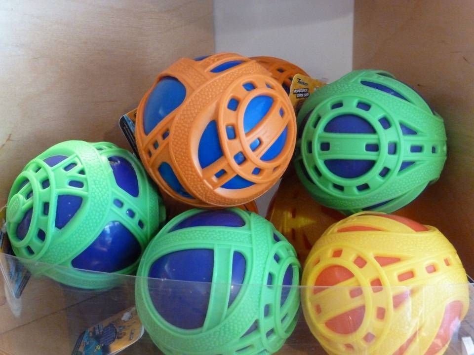 Des balles de jouets colorées, bleues, vertes, oranges et jaunes, empilées dans une boîte en carton.