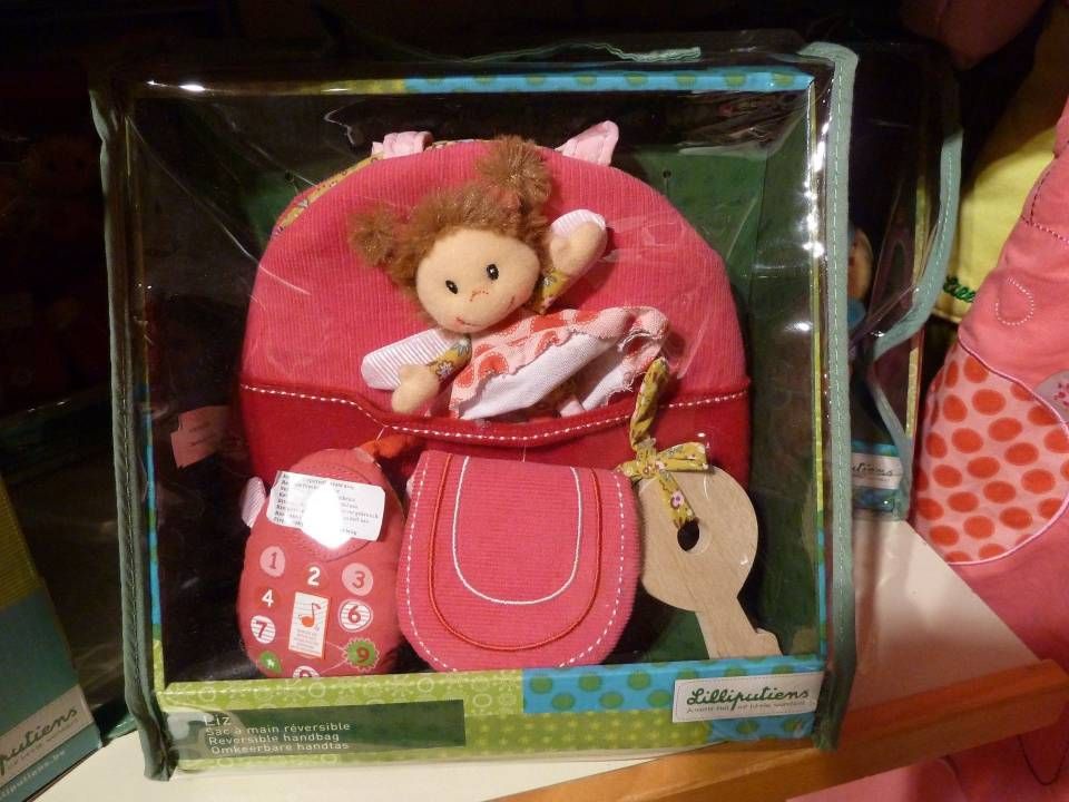 Poupée en plastique dans un étui rose en forme de sac à main avec un porte-clés sur une étagère de magasin