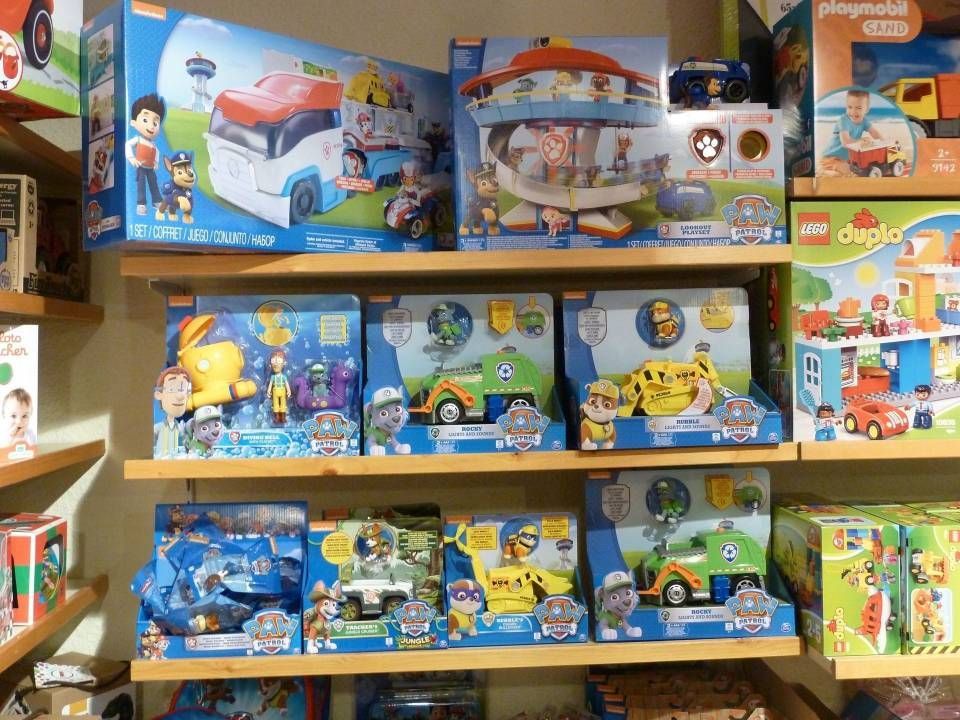Des étagères colorées de magasin de jouets remplies de coffrets de jeux et de véhicules à l'effigie de personnages de dessins animés.