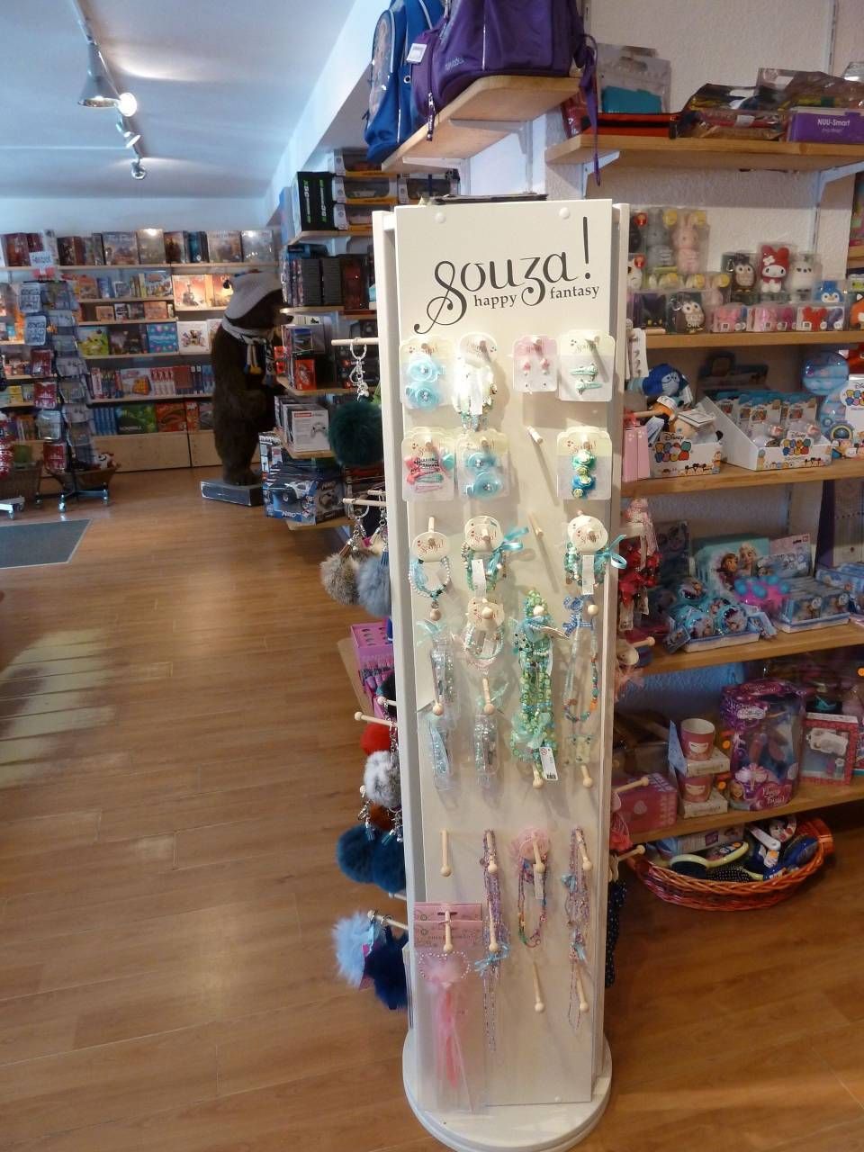 Présentoir rotatif blanc exposant des bijoux fantaisie et accessoires colorés dans un rayon de magasin