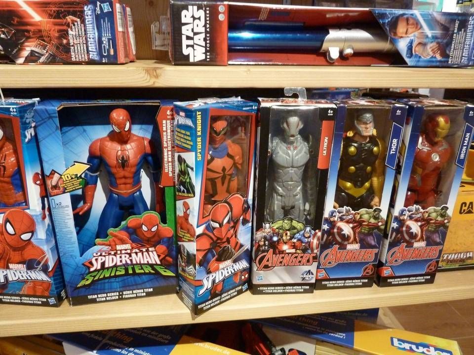 Des figurines Spider-Man et Avengers dans des boîtes colorées alignées sur une étagère de magasin