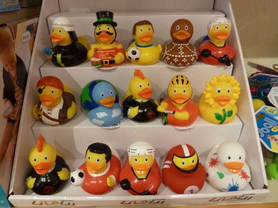 Étagère remplie de figurines de canards colorées et de figurines à tête branlante disposées en rangées sur des étagères blanches