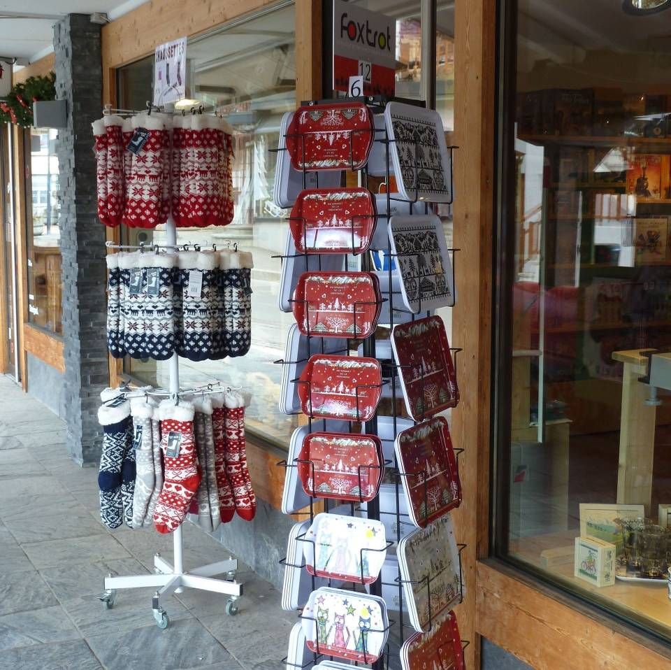 Présentoir de chaussettes tricotées suspendues, rouges, blanches et noires, devant une vitrine de magasin