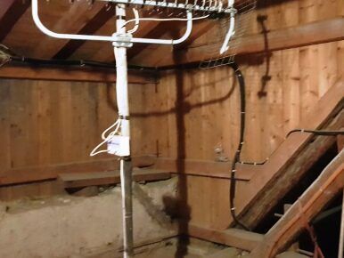 Ein Dachboden mit einer Fernsehantenne, Holzwänden und einem Schatten, der auf das Holz fällt.