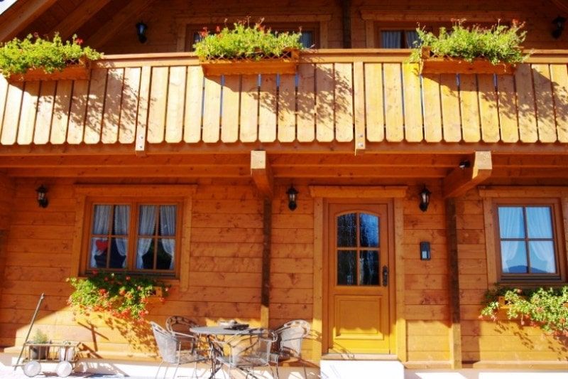Äußeres Äußeres einer Holzhütte mit Balkon, Blumenkästen und Tür.