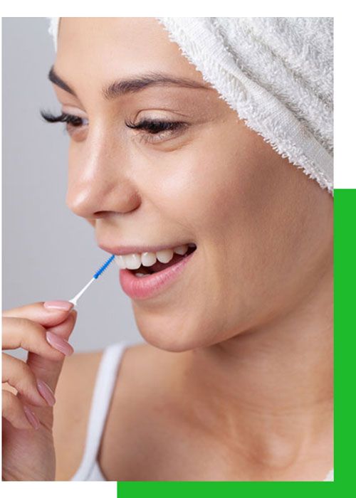 Una mujer con una toalla envuelta alrededor de su cabeza se limpia los dientes con un palillo.