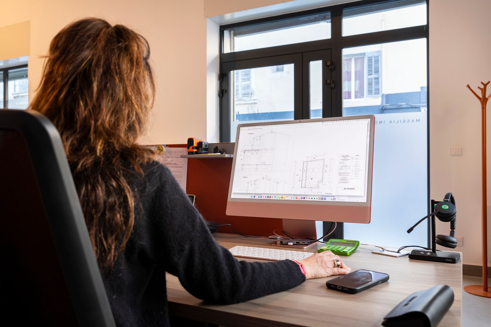 Femme qui travail sur des plan de maison sur un ordinateur dans son bureau