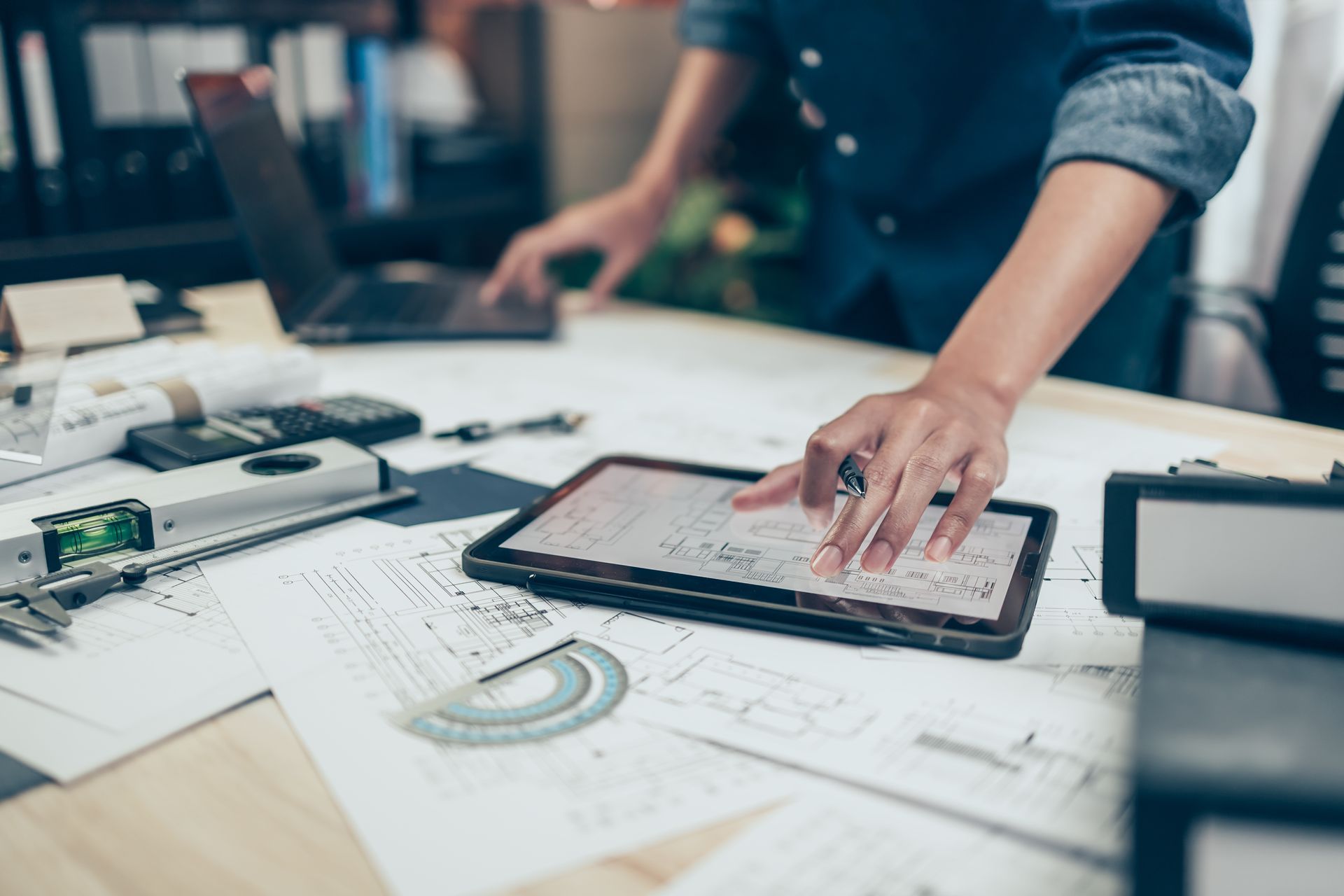 Gros plan sur les mains d'un expert qui travaille sur des plans de maison avec plans et des outils informatiques de pointe