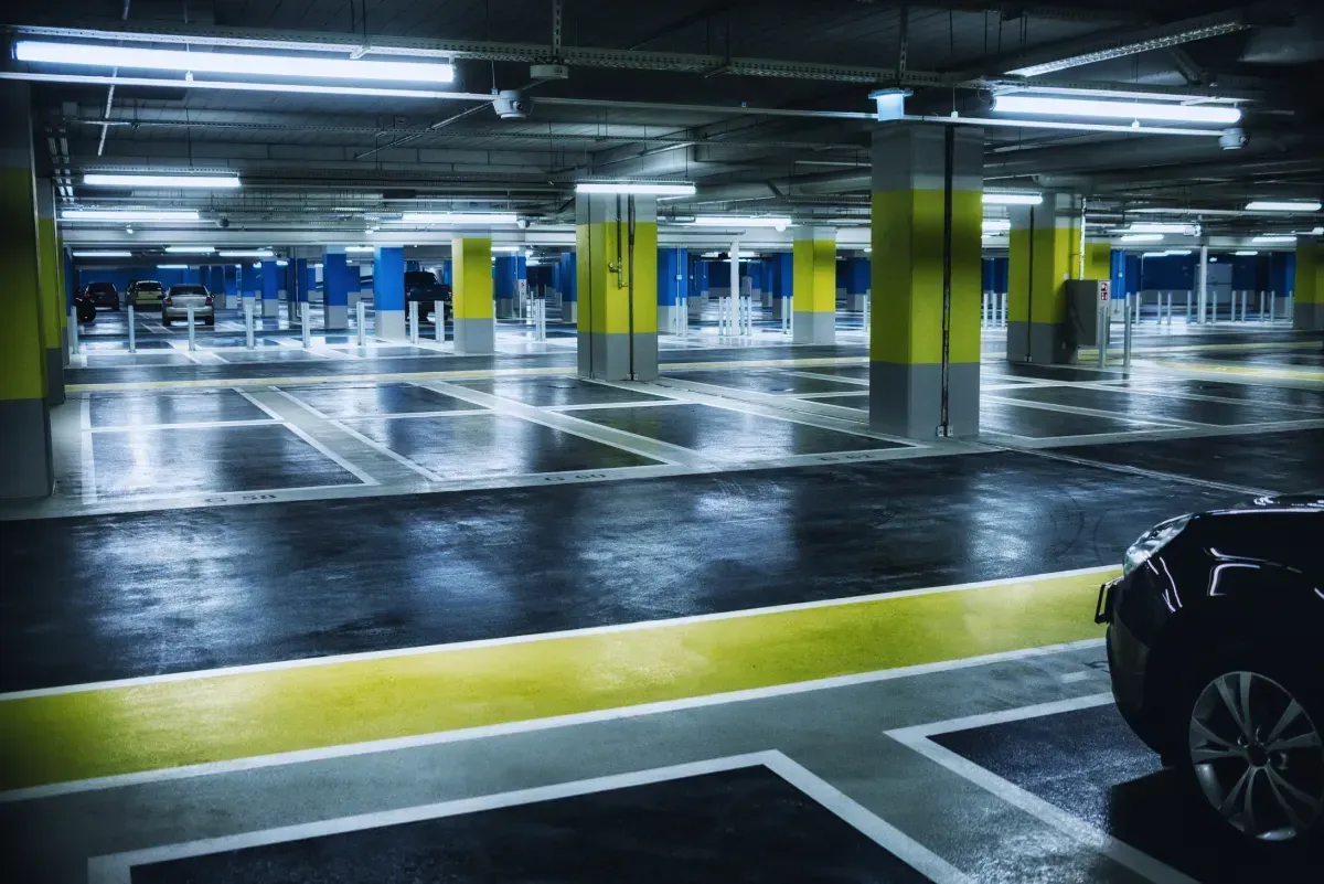 Estacionamiento vacío con piso mojado. Pilares y líneas amarillas para los espacios de estacionamiento.