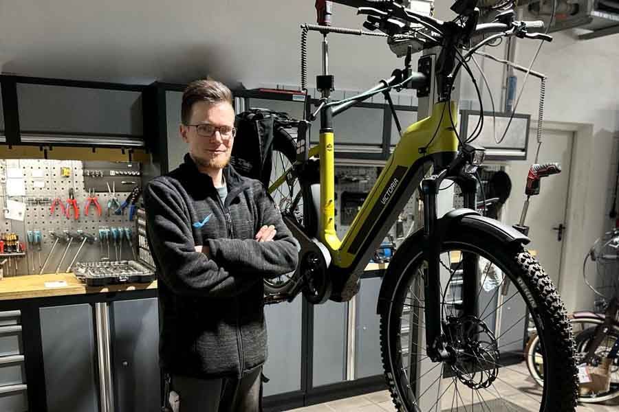 Ein Mann steht neben einem Fahrrad in einer Garage.