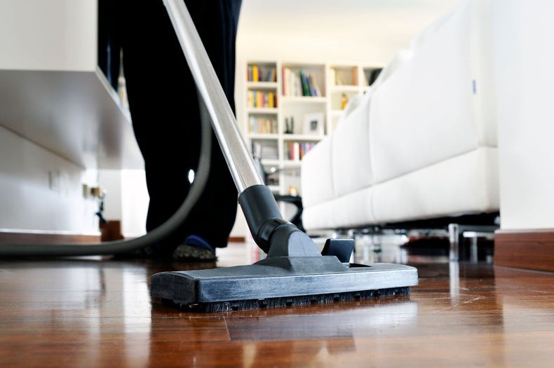 Une personne passant l'aspirateur sur un parquet dans un salon.