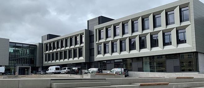 Modernes mehrstöckiges Gebäude mit geometrischem Design, bewölkter Himmel im Hintergrund.