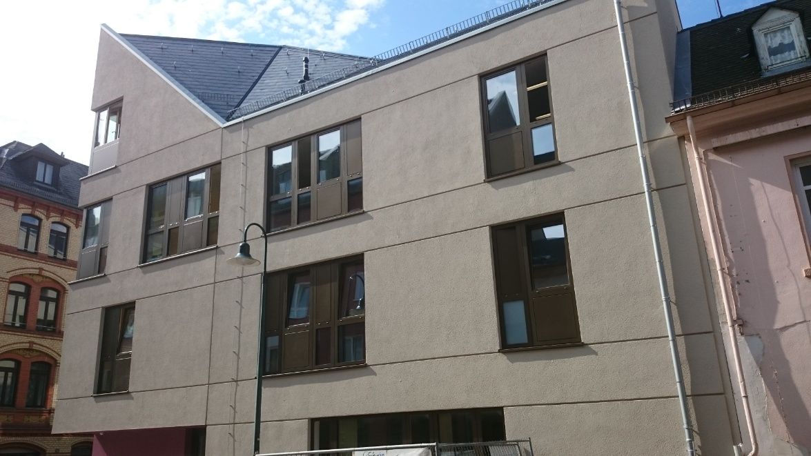 Beiges Gebäude mit dunkel gerahmten Fenstern vor blauem Himmel.