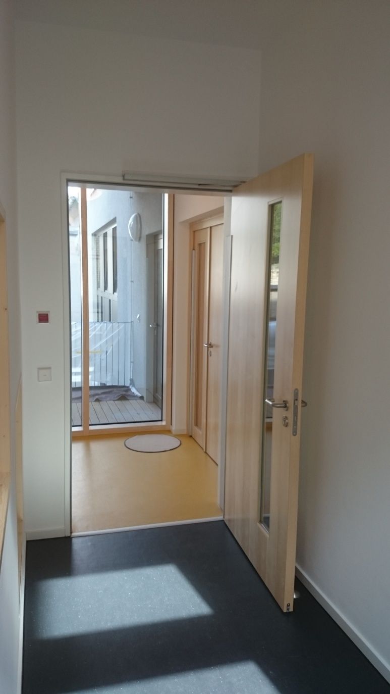 Inneneingang mit offener Tür und Fensterblick auf einen Außenbereich.