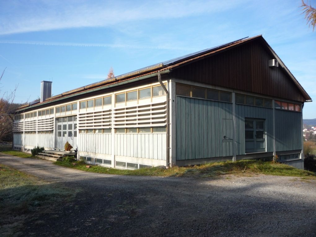 Ein hellblaues und braunes Holzgebäude mit Lamellenfassade an einem sonnigen Tag.