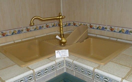 Un fregadero de cocina con grifo de latón en un baño.