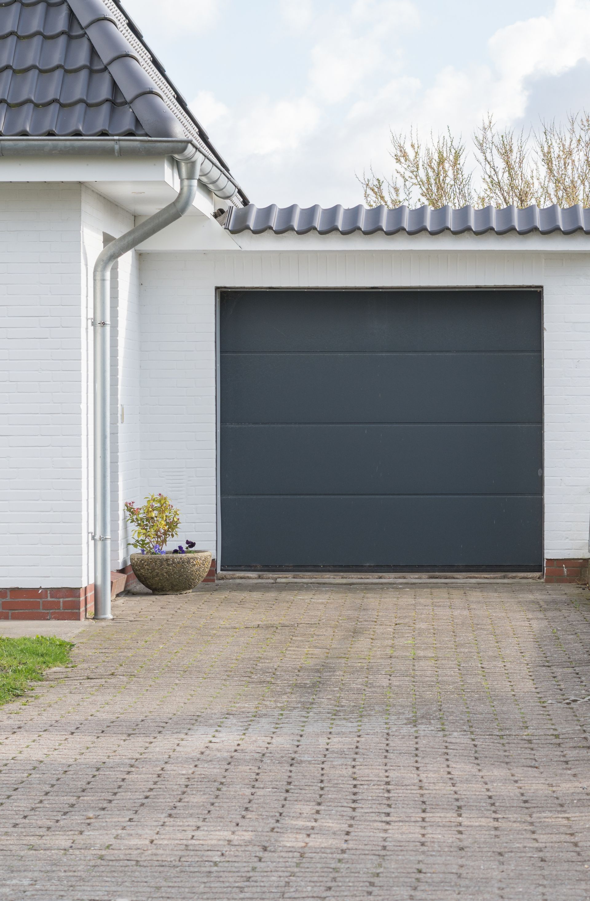 Une maison blanche avec une porte de garage gris foncé.
