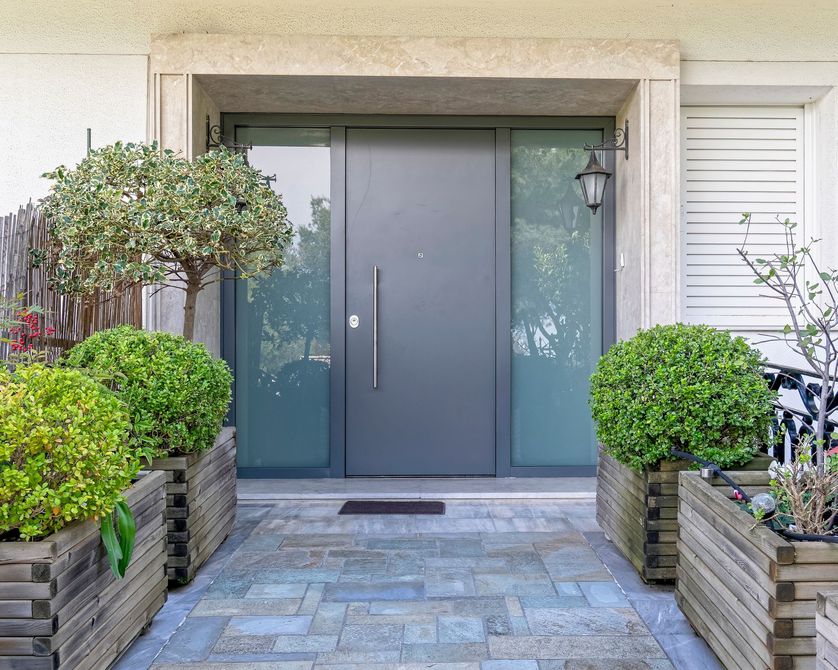 Une porte d'entrée moderne gris foncé avec des panneaux latéraux en verre.