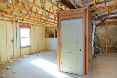 Una habitación en una casa en construcción con una puerta y ventanas.
