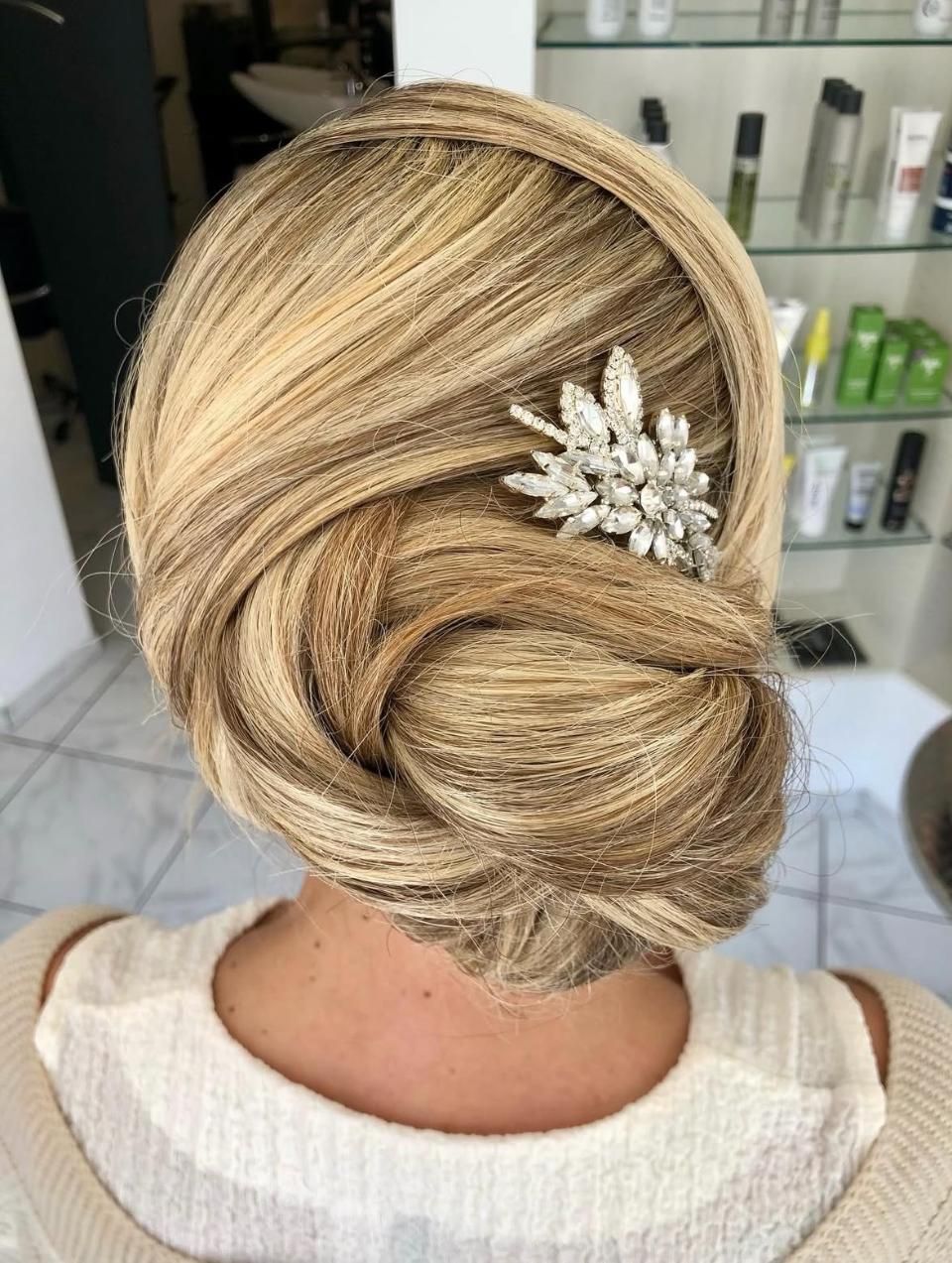 Blonde Hochsteckfrisur mit einer juwelenbesetzten Haarspange im Salon-Ambiente
