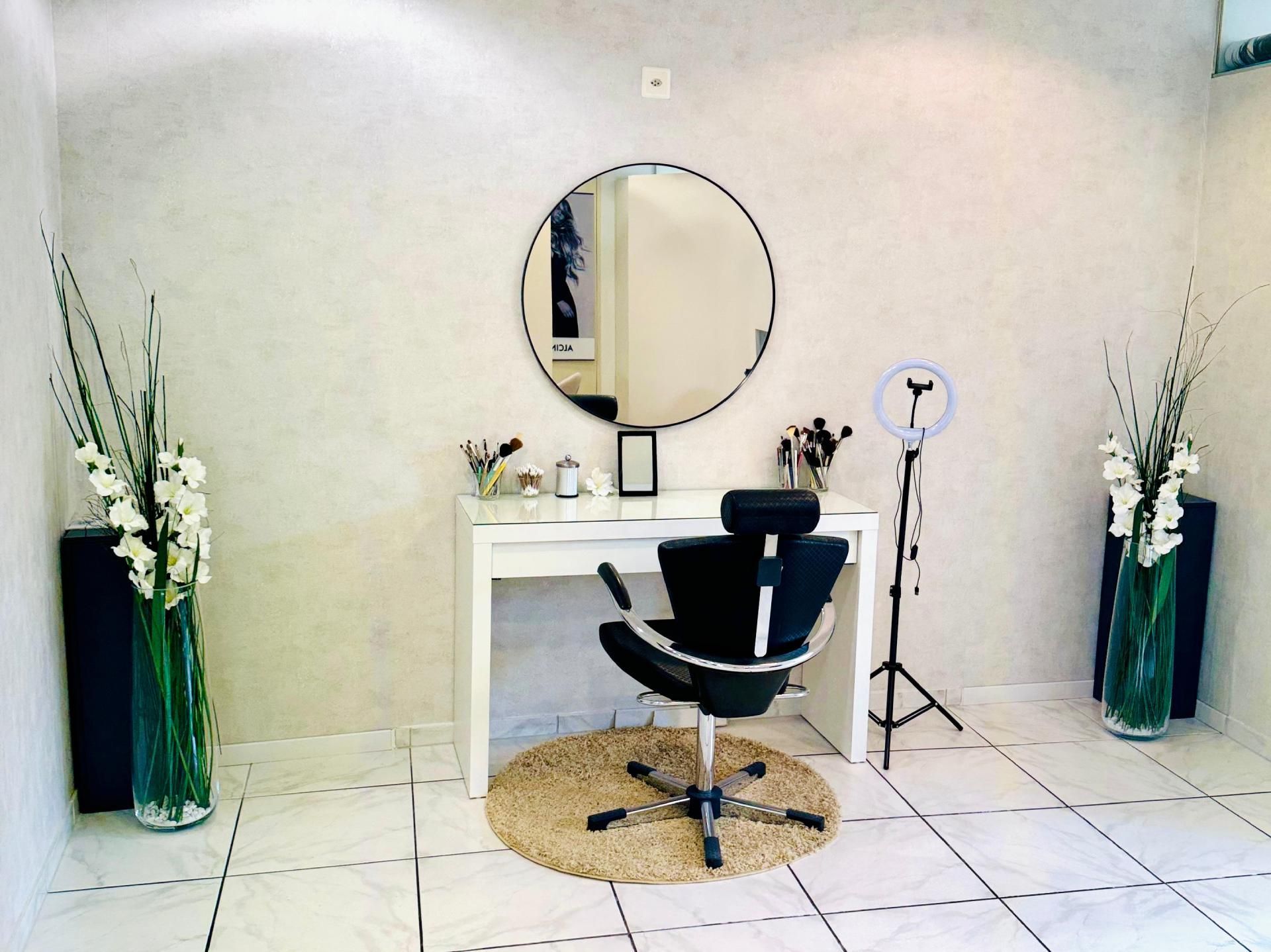 Salonarbeitsplatz mit weissem Schreibtisch, rundem Spiegel, schwarzem Stuhl.