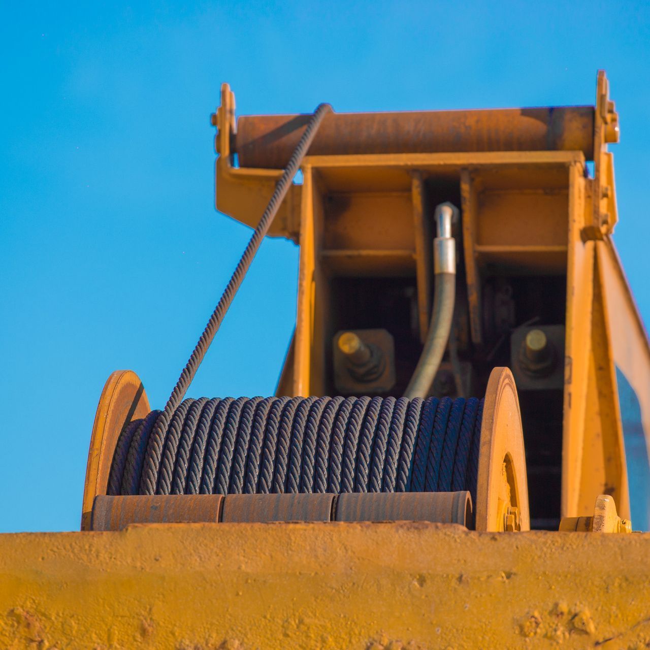 Un primer plano de una excavadora amarilla con un cabrestante acoplado a ella.