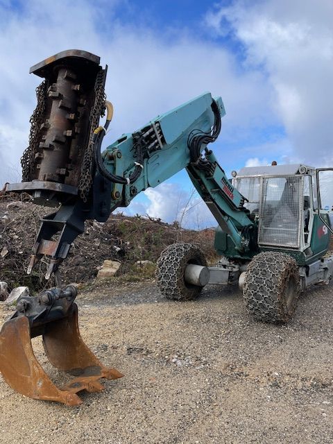 Una excavadora grande está sentada encima de un campo de tierra.
