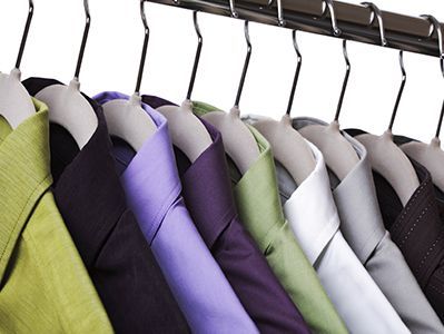 Fila de chaquetas en perchas en un perchero, con prendas grises, moradas, verdes y negras