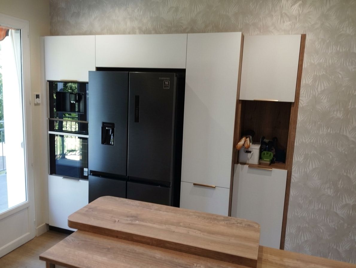 Cuisine avec un réfrigérateur noir, des placards blancs et un îlot en bois au premier plan