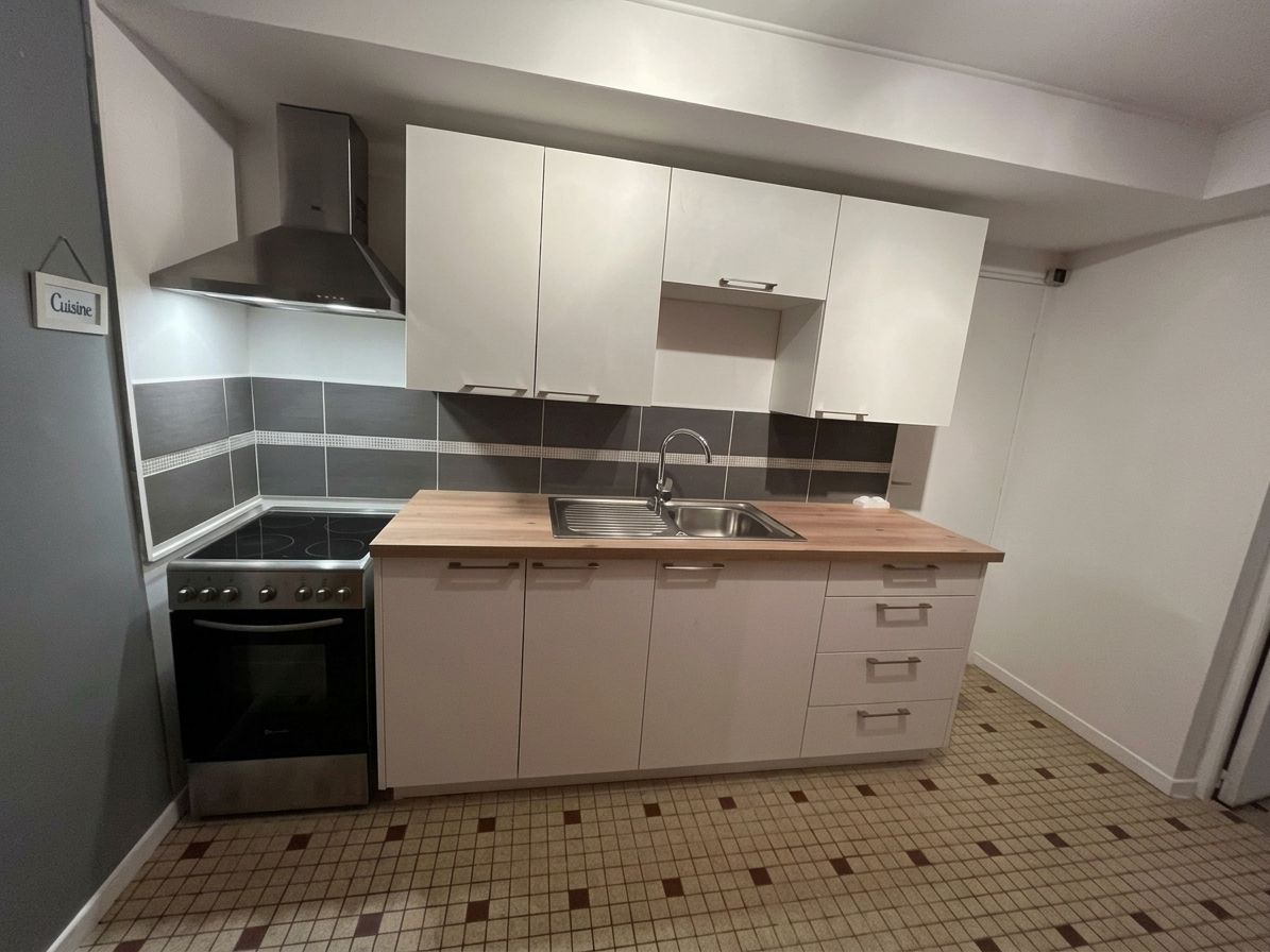 Petite cuisine avec des placards blancs, une hotte en acier inoxydable, des plans de travail en bois et un sol carrelé.