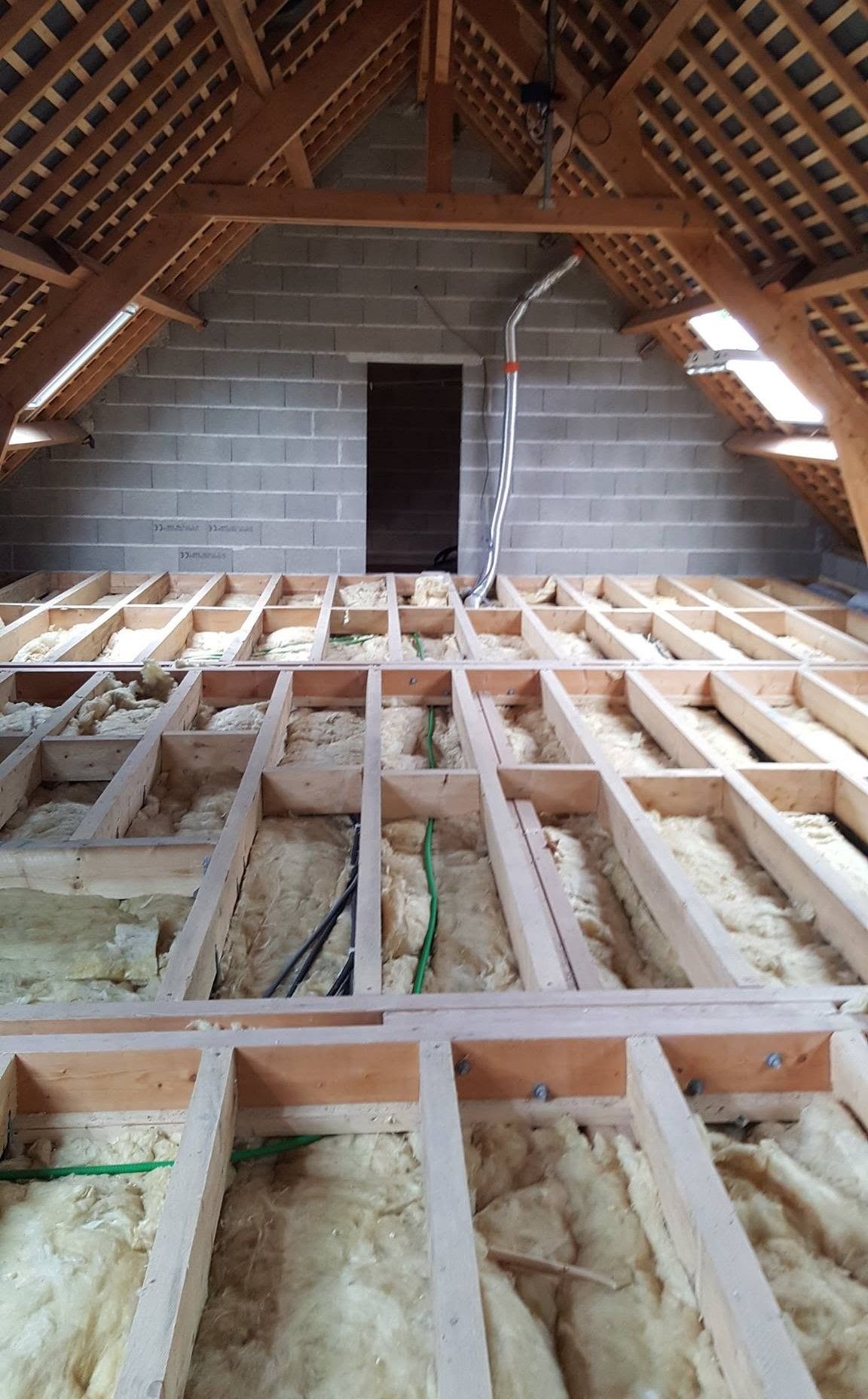 Combles en cours d’aménagement, avec la charpente en bois et l’isolation apparentes