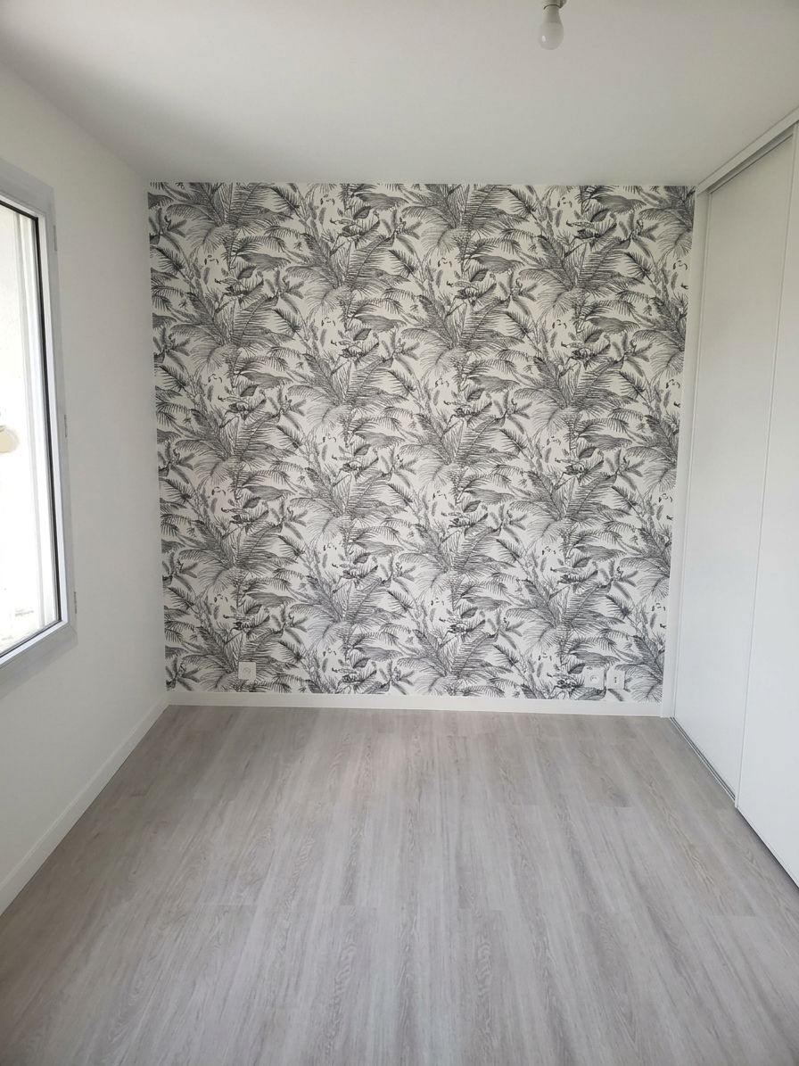 Pièce moderne vide avec un sol gris, des murs blancs et un mur d’accent à motifs noirs et blancs