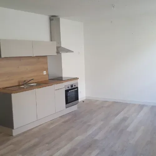 Cuisine moderne vide avec des placards blancs, une crédence en bois et un parquet clair en bois