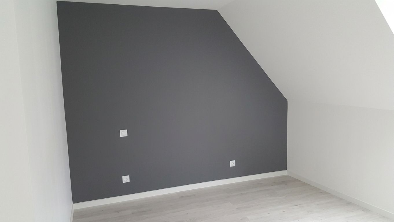 Coin vide avec un mur d’accent gris foncé, des murs blancs et un parquet clair.