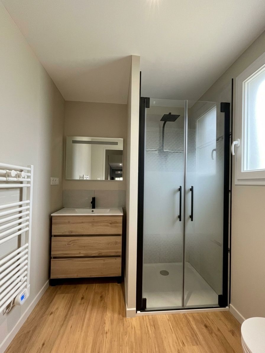 Salle de bains moderne avec meuble vasque en bois, miroir, cabine de douche, porte-serviettes blanc et parquet clair