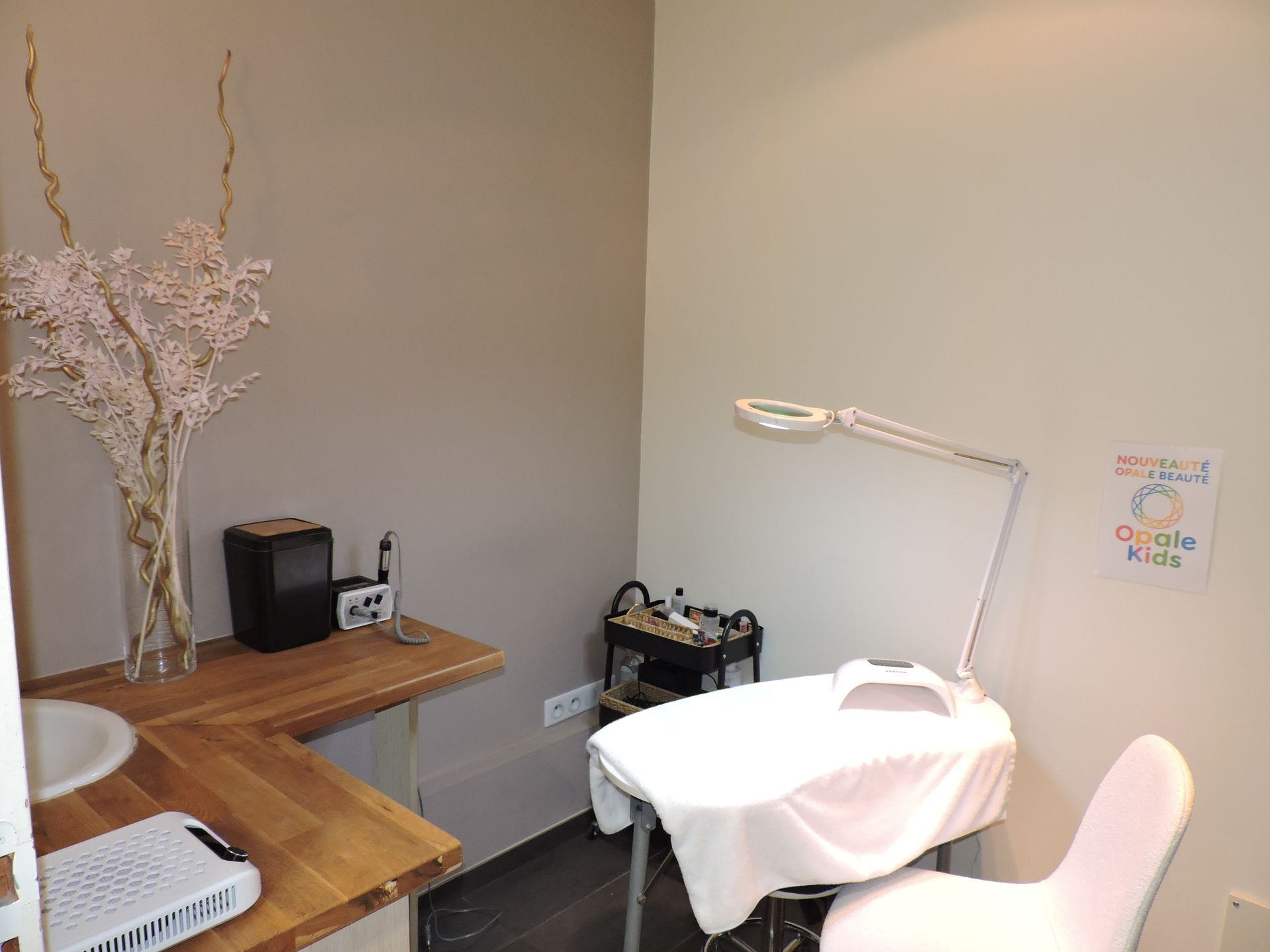 Poste de manucure avec une table, une lampe et une chaise. Bureau en bois avec vase et matériel.