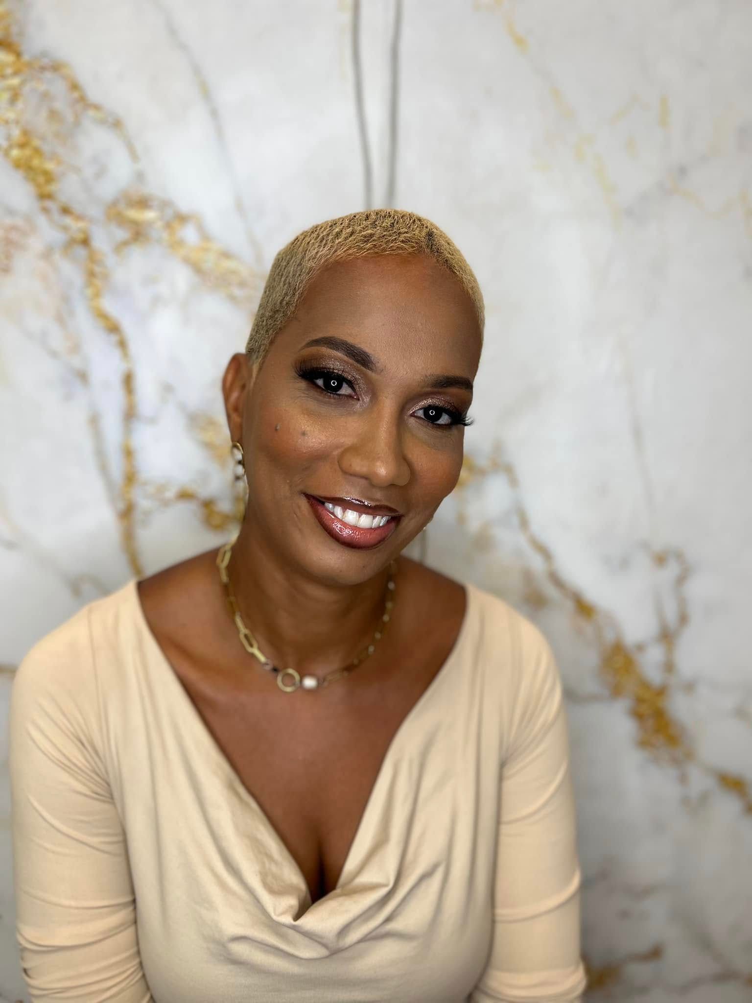 Femme souriante en haut beige sur fond de marbre blanc
