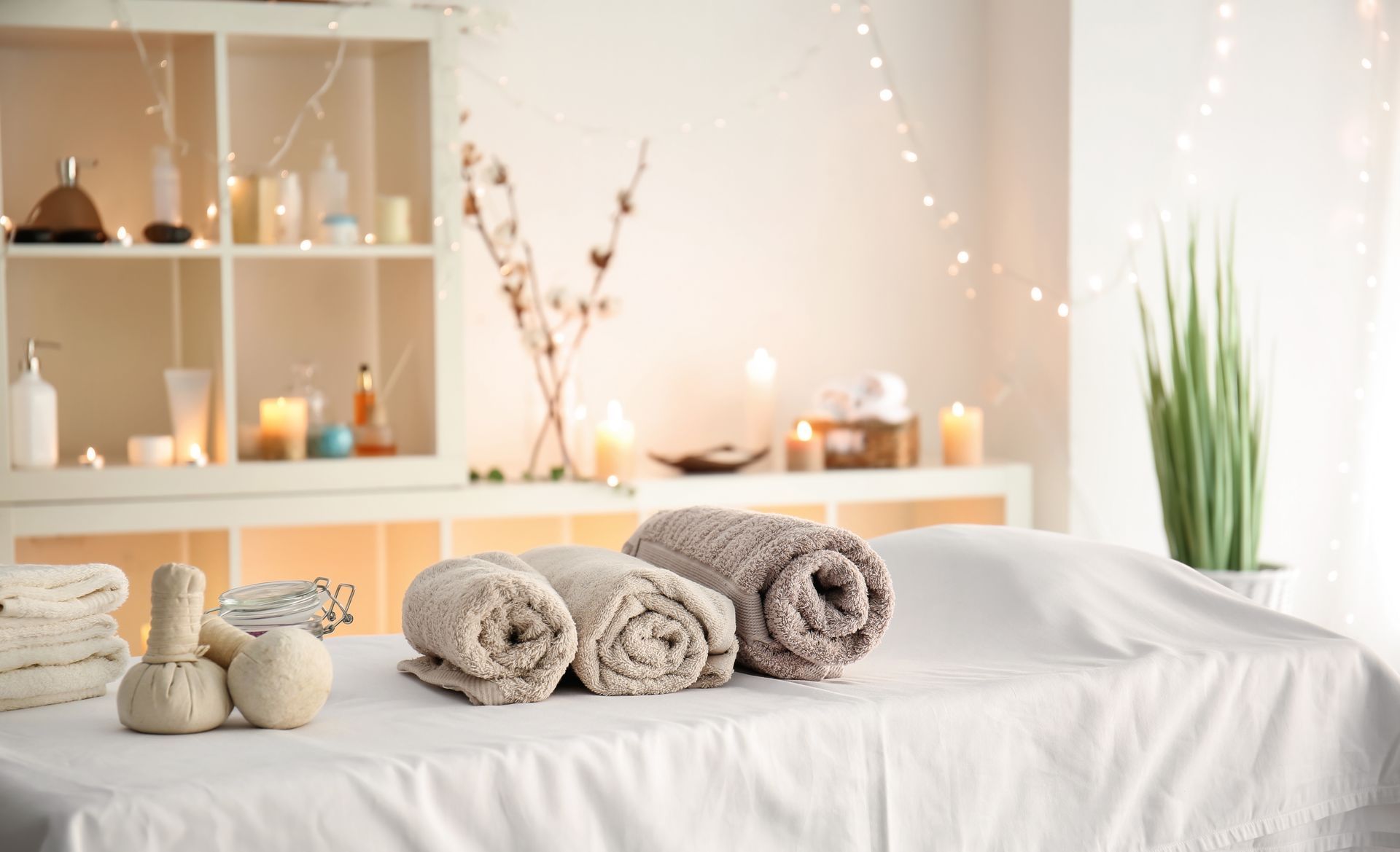 Salle de massage spa avec serviettes roulées, bougies et décoration blanche douce