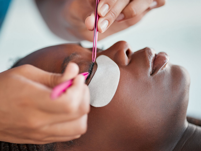 Application de faux cils à la pince lors d'une séance de maquillage.