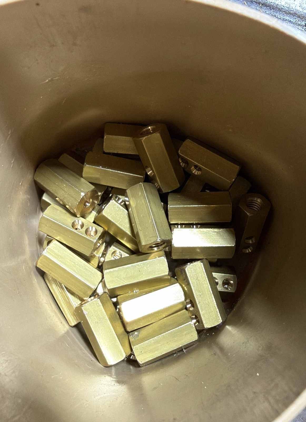 Pequeños lingotes dorados apilados dentro de un recipiente metálico