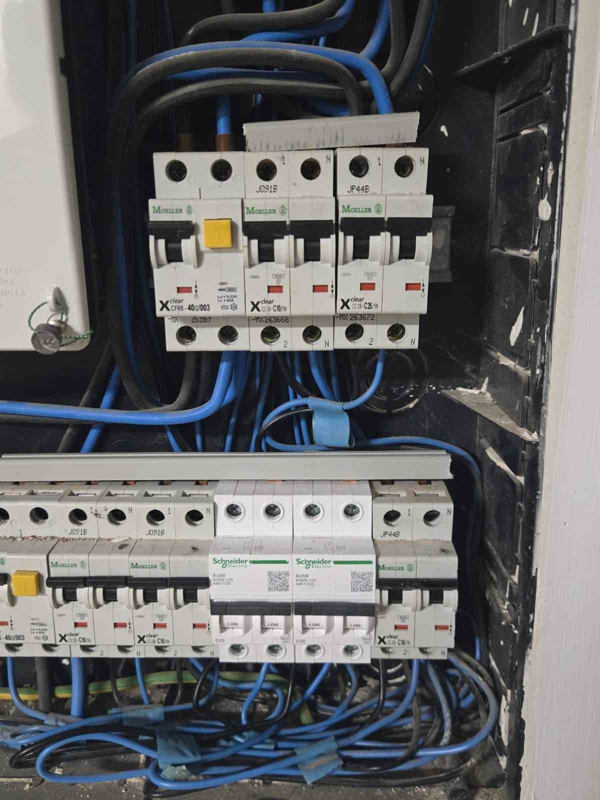 Cuadro eléctrico con filas de disyuntores y cableado azul en el interior de una caja metálica