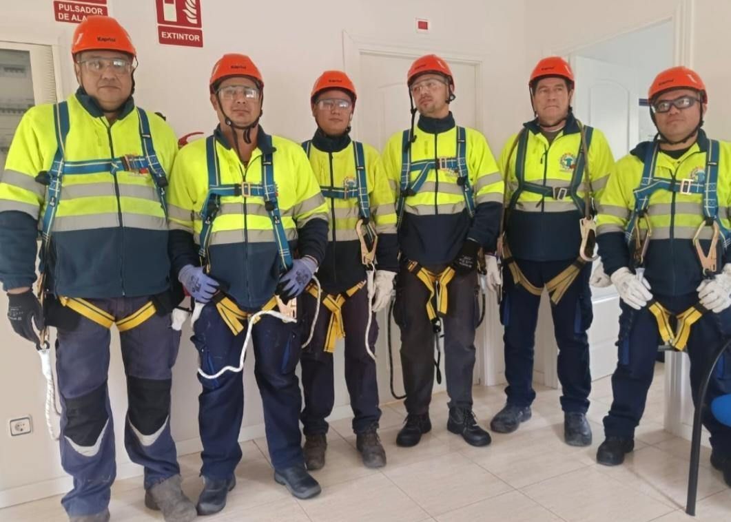 Seis trabajadores de la construcción con equipo de seguridad, de pie en el interior con cascos y chalecos reflectantes