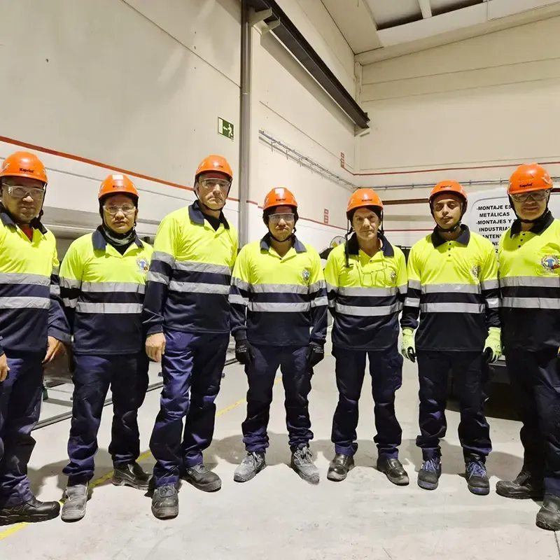 Siete personas con chalecos de seguridad y cascos se encuentran en un almacén.