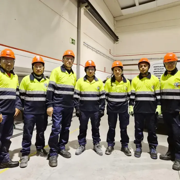 Siete personas con chalecos de seguridad y cascos se encuentran en un almacén.