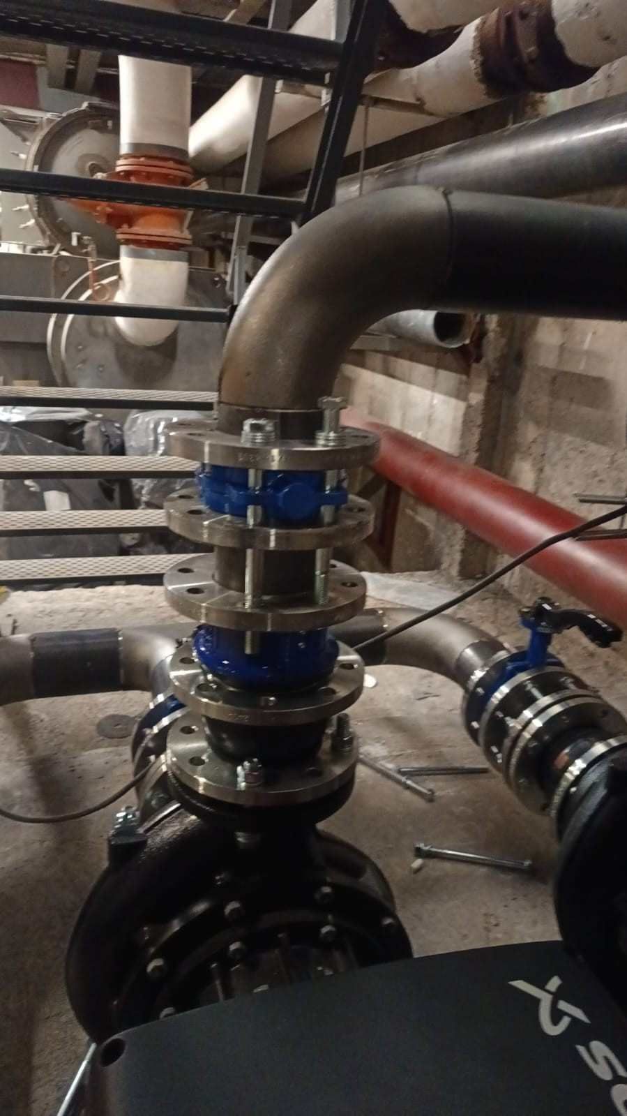 Tuberías y válvulas industriales con bridas azules en una sala de servicios