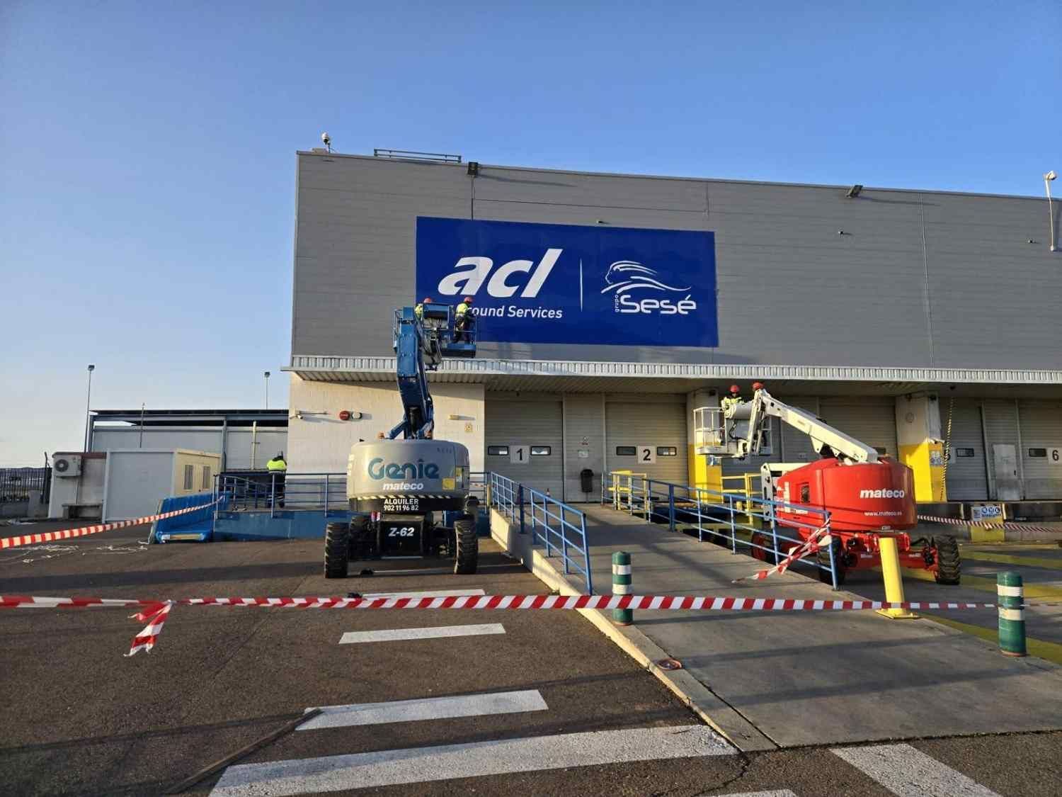 Exterior de un almacén de Blue ACI con vehículos utilitarios, trabajadores.