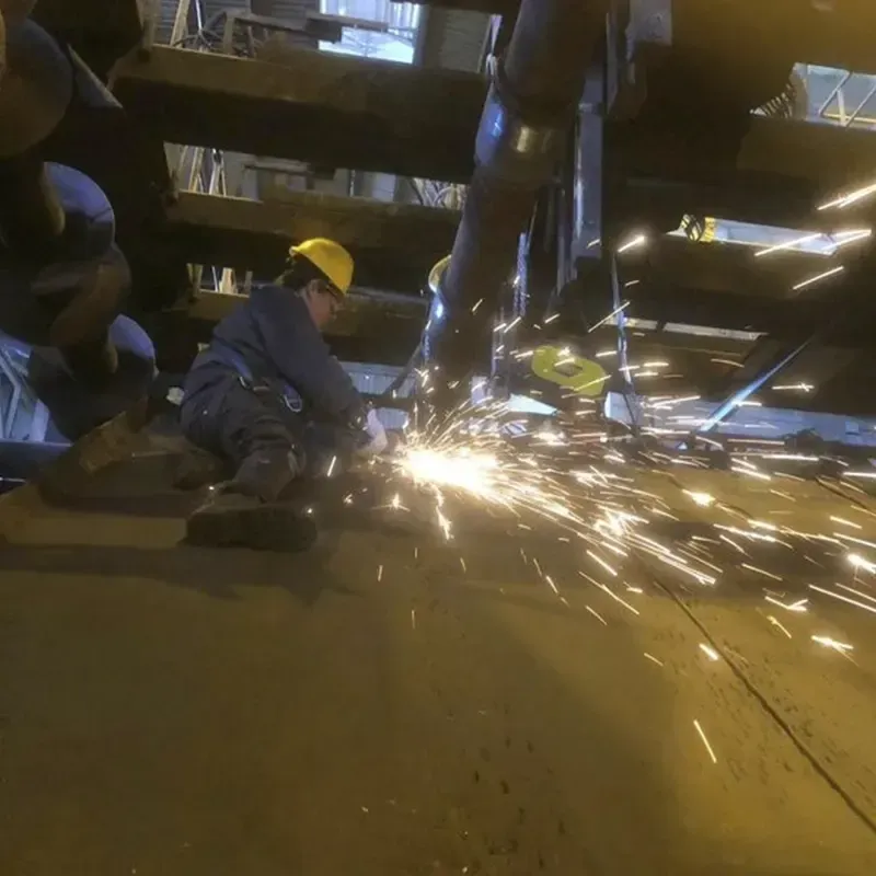 Una persona con equipo de seguridad utiliza una amoladora, generando chispas, en un entorno industrial.