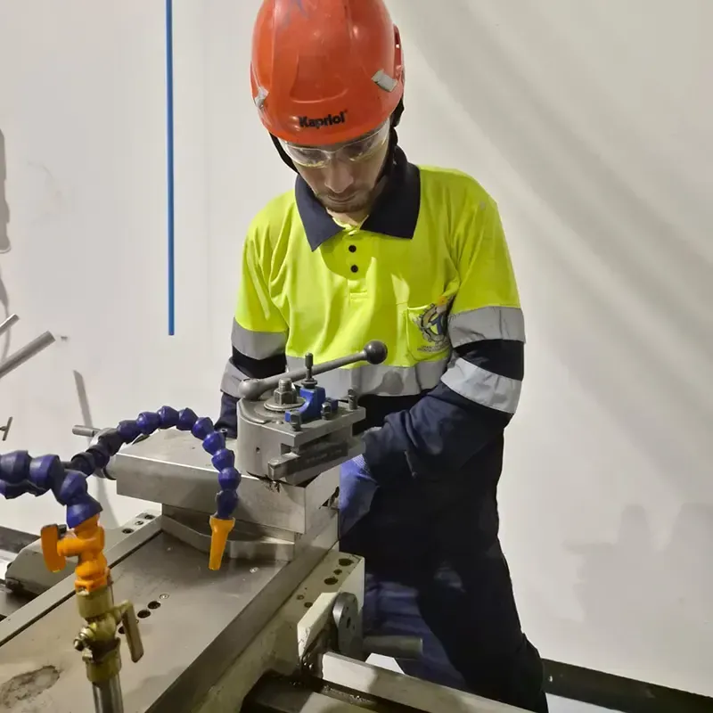 Persona con equipo de seguridad utilizando un torno de metal en un taller.