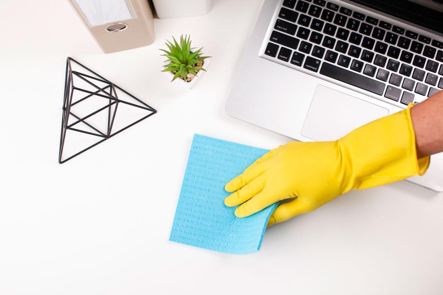 Una persona que lleva guantes amarillos está limpiando un escritorio con una esponja.